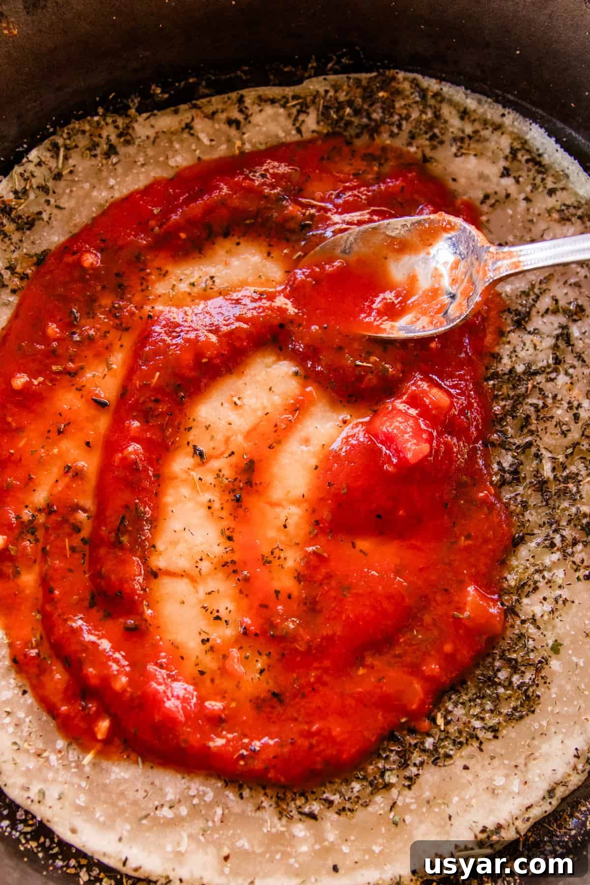 Sourdough Sausage Pizza Recipe with Crispy Golden Crust 6 Spreading pizza sauce on a sourdough pizza crust.