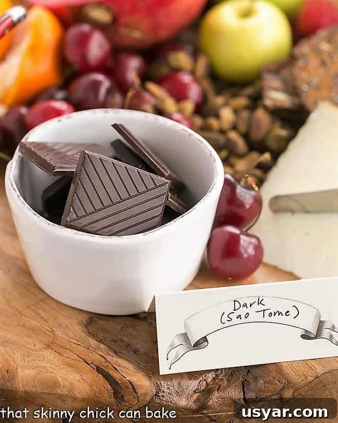 Chocolate Dessert Board - an elegant way to end a meal with top notch chocolates, fruit and cheeses artfully displayed for a jaw dropping presentation! Chocolate squares in a white bowl with cherries and pistachios