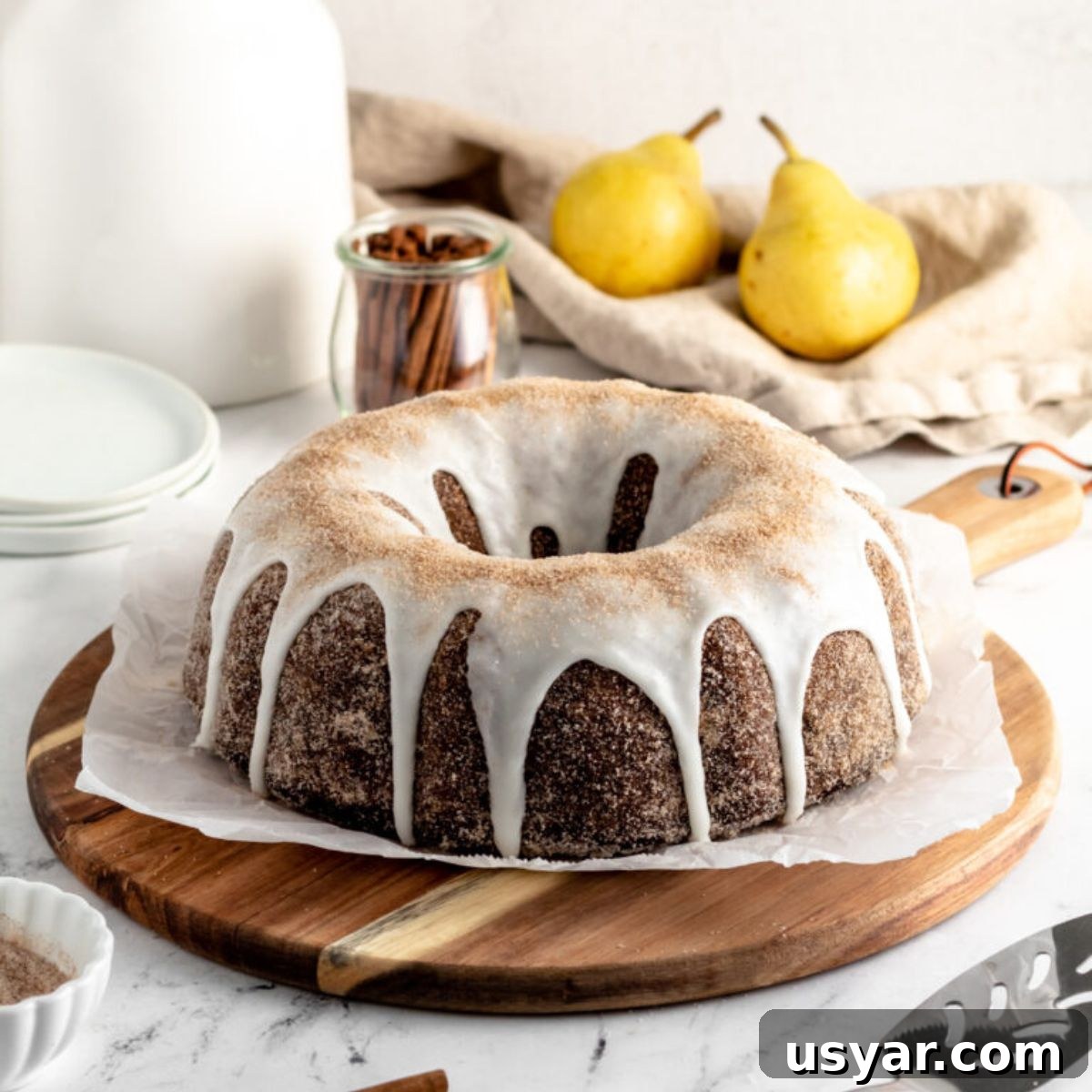 Moist Chocolate Pear Cake Recipe with Fresh Pears 2 Chocolate bundt cake coated with cinnamon sugar and icing, two pears and some cinnamon sticks.