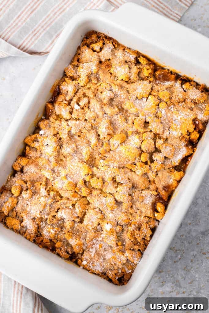 Mom's 90s Gluten-Free Peach Cobbler Recipe 3 Top down image of peach cobbler in a casserole dish with gluten free topping, caramelized sugar on top, and golden peach filling