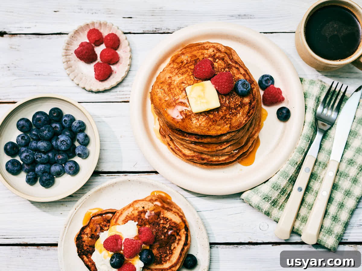 High-Protein Cottage Cheese Pancakes Recipe 3 High protein Cottage Cheese Pancakes on plates topped with berries, butter, maple syrup on a breakfast table.