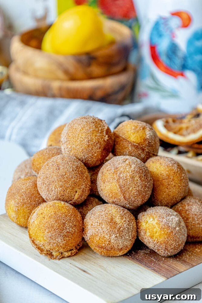 Homemade Baked Cinnamon Sugar Donut Holes Recipe 2 A stack of 10 minute cinnamon sugar donuts on a cutting board.