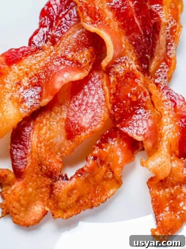A close up of bacon baked in the oven on a white plate.