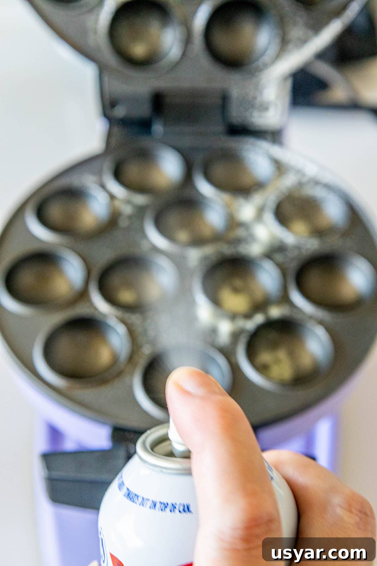 Homemade Baked Cinnamon Sugar Donut Holes Recipe 8 picture of nonstick spray being sprayed onto cake pop pan