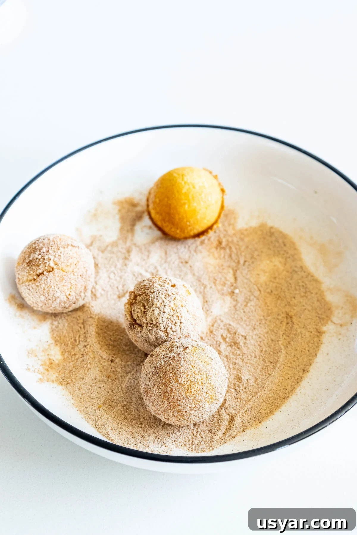 Homemade Baked Cinnamon Sugar Donut Holes Recipe 10 picture of donut holes being rolled in a bowl of cinnamon sugar