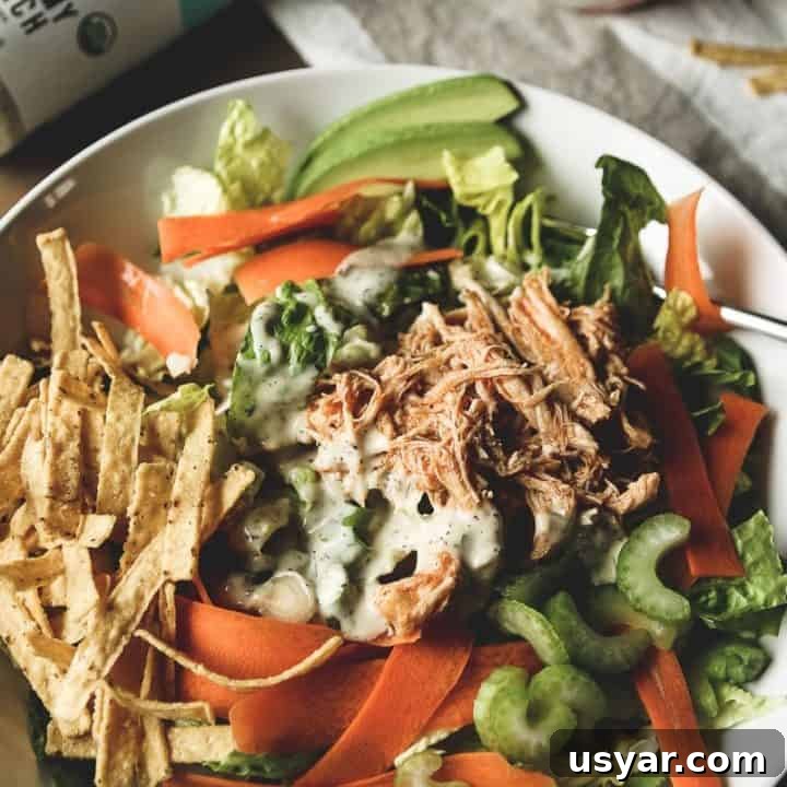 a bowl full of salad with celery, green onion, carrots, shredded buffalo chicken and ranch dressing