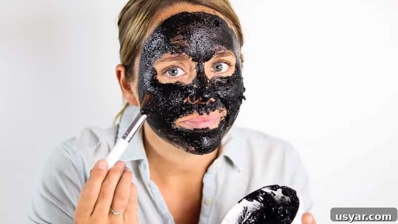 Brushing a homemade charcoal mask onto the face.