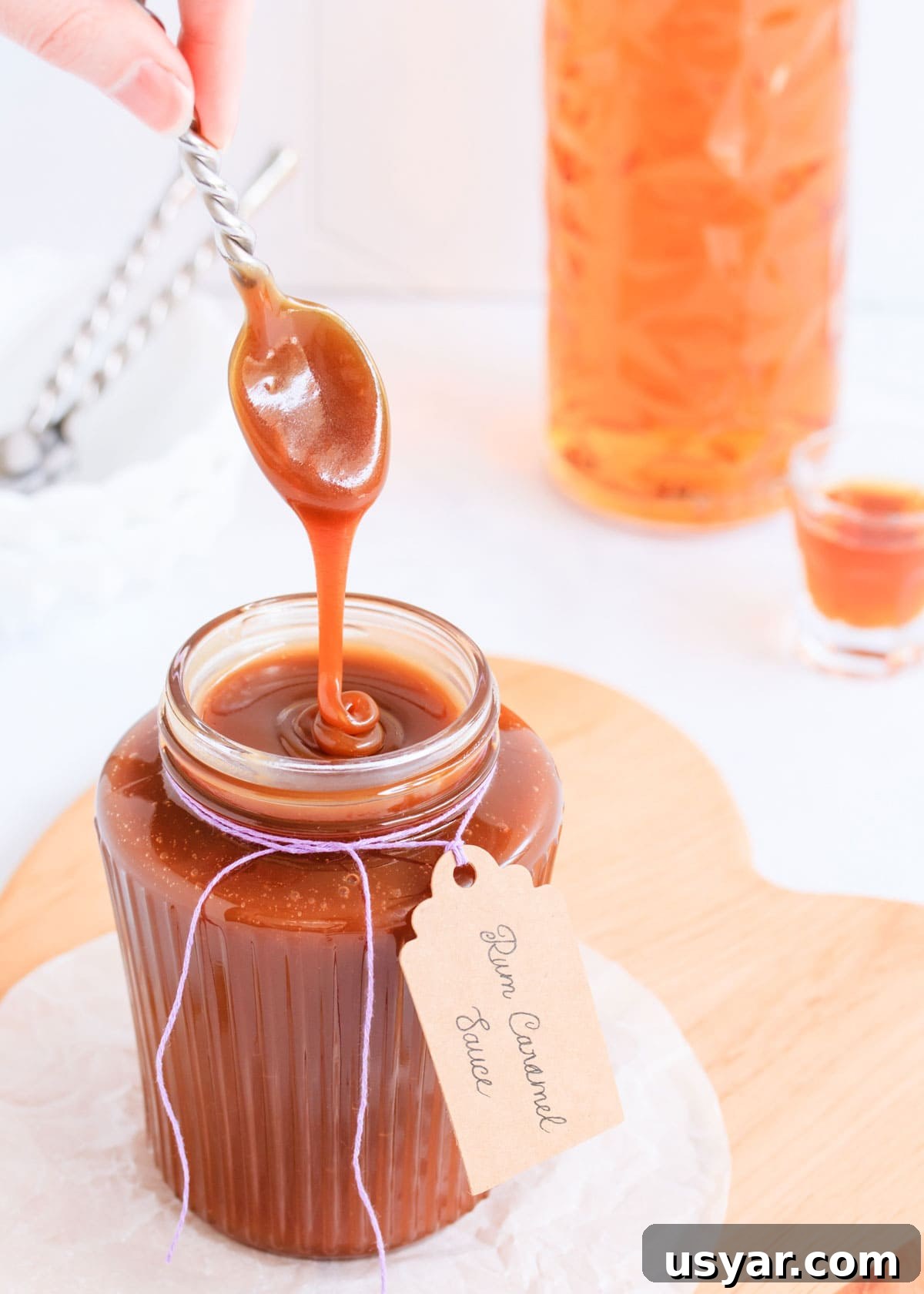 Rum Caramel Sauce Recipe 15 Rum caramel sauce falling from a spoon in a thick ribbon back into a ribbed glass jar.