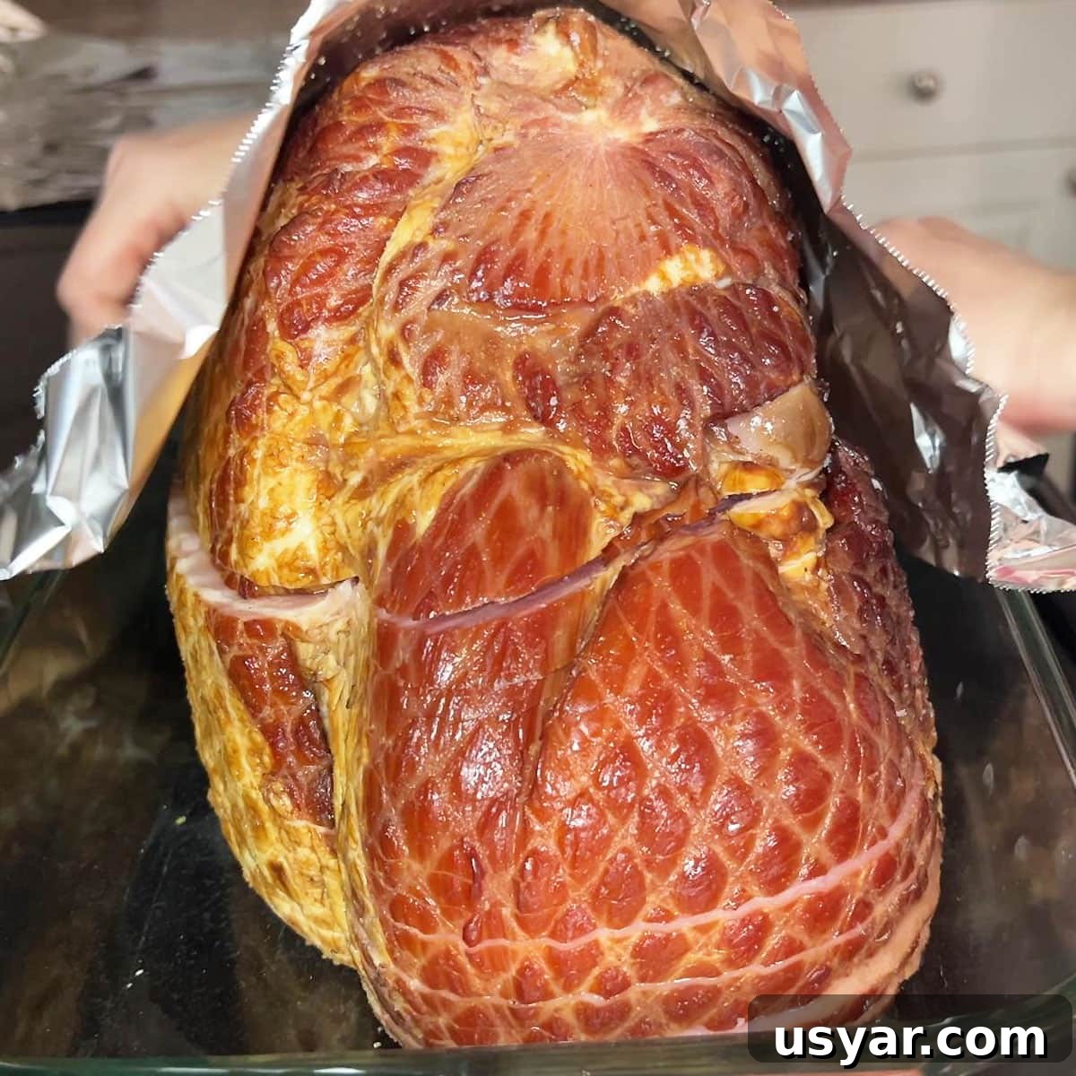 Coca Cola Glazed Ham Recipe 5 Covering a spiral sliced ham in a baking dish with aluminum foil.