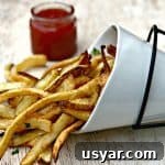 Crispy Homemade Air Fryer French Fries 11 air fryer fries spread out on a brown surface with ketchup