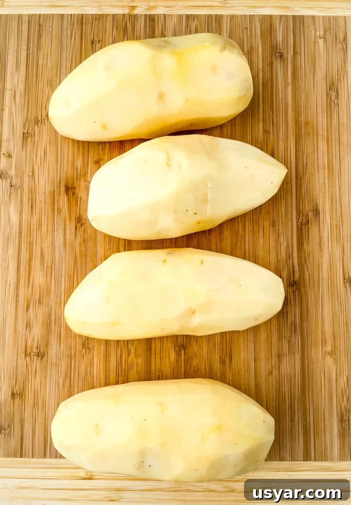 Crispy Homemade Air Fryer French Fries 3 raw russet potatoes peeled on a bamboo cutting board