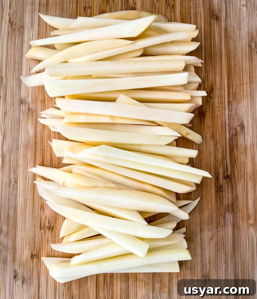 Crispy Homemade Air Fryer French Fries 4 raw sliced potatoes on a cutting board