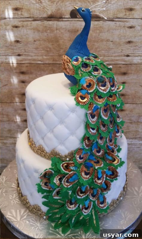 Custom Cakes for Weddings, Birthdays and Special Events 6 2 tiered white fondant cake topped with a blue peacock, icing feathers cascading down cake.