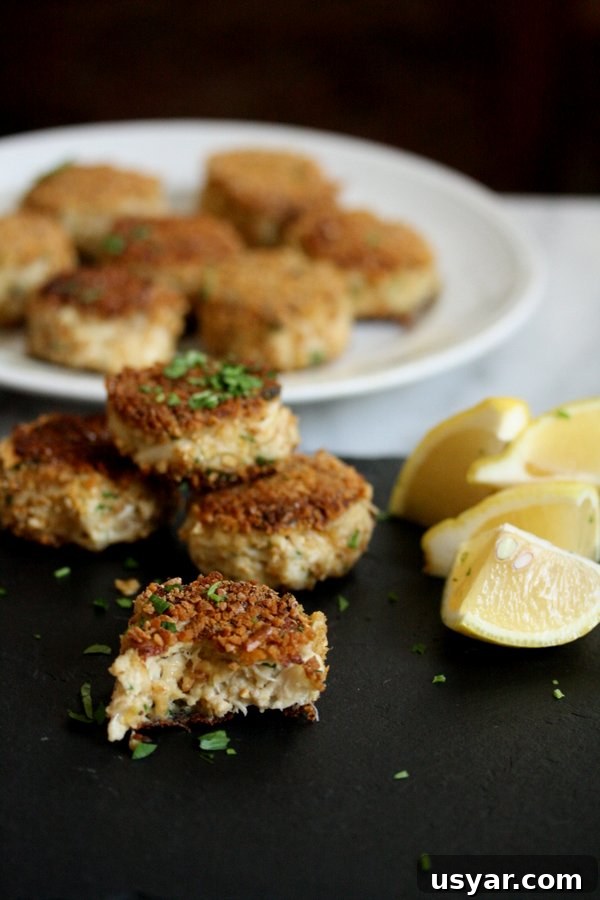 Pretzel-Crusted Gluten-Free Crab Cakes Recipe 2 gluten-free crab cakes with pretzel crust on a plate with lemon wedges