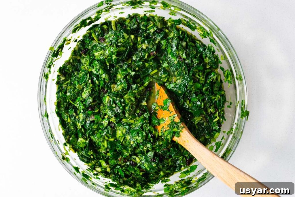 Kuku Sabzi Persian Herb Frittata Recipe 11 Kuku sabzi batter with lots of fresh herbs and just enough eggs to coat the herbs and greens with a wooden spoon in a glass bowl viewed from above.