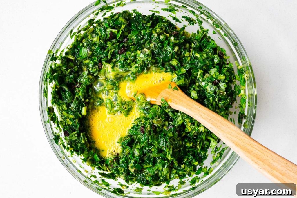 Kuku Sabzi Persian Herb Frittata Recipe 10 Whisked eggs added to a bowl of finely chopped greens viewed from above.