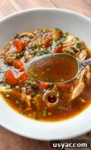 A close-up of No Water Chicken Soup with shredded chicken and vegetables.