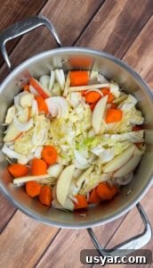 A stainless steel pot with chopped vegetables for no water chicken soup.