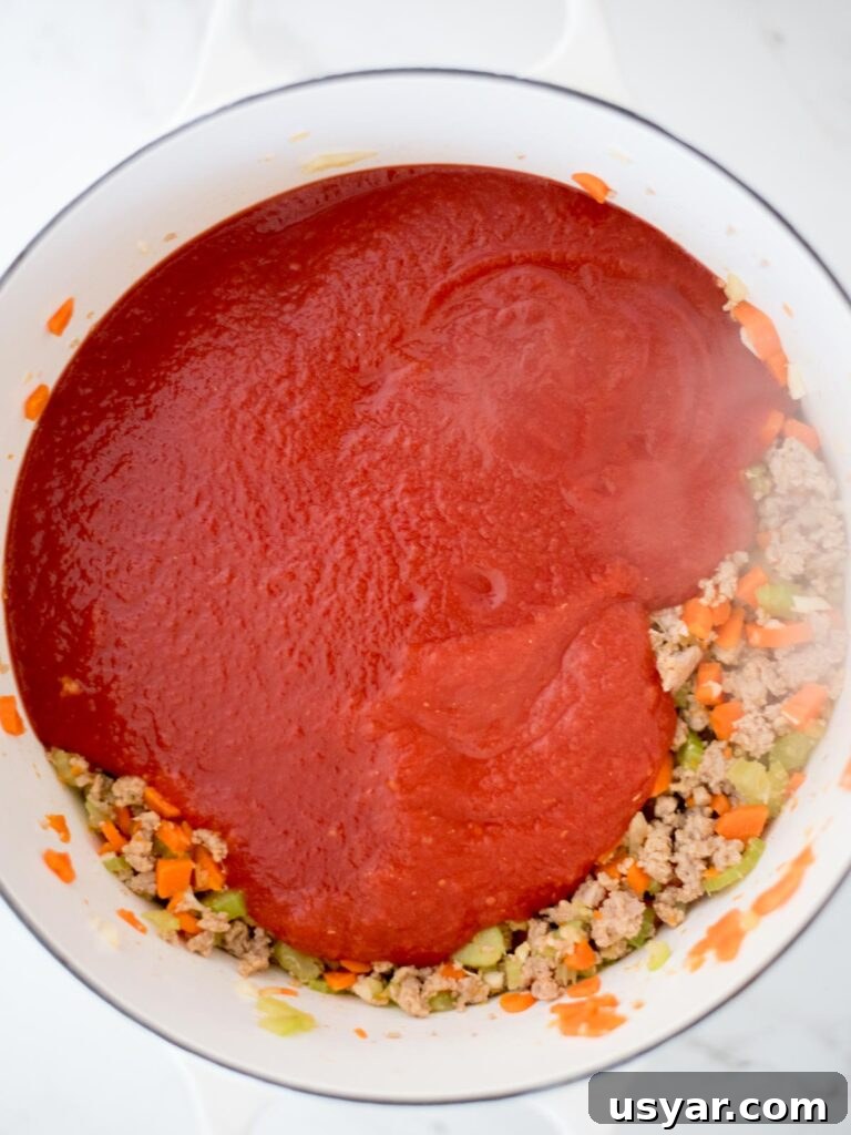 Authentic Italian Pasta e Fagioli Soup Recipe 9 crushed tomatoes and tomato sauce added to dutch oven with sausage mix