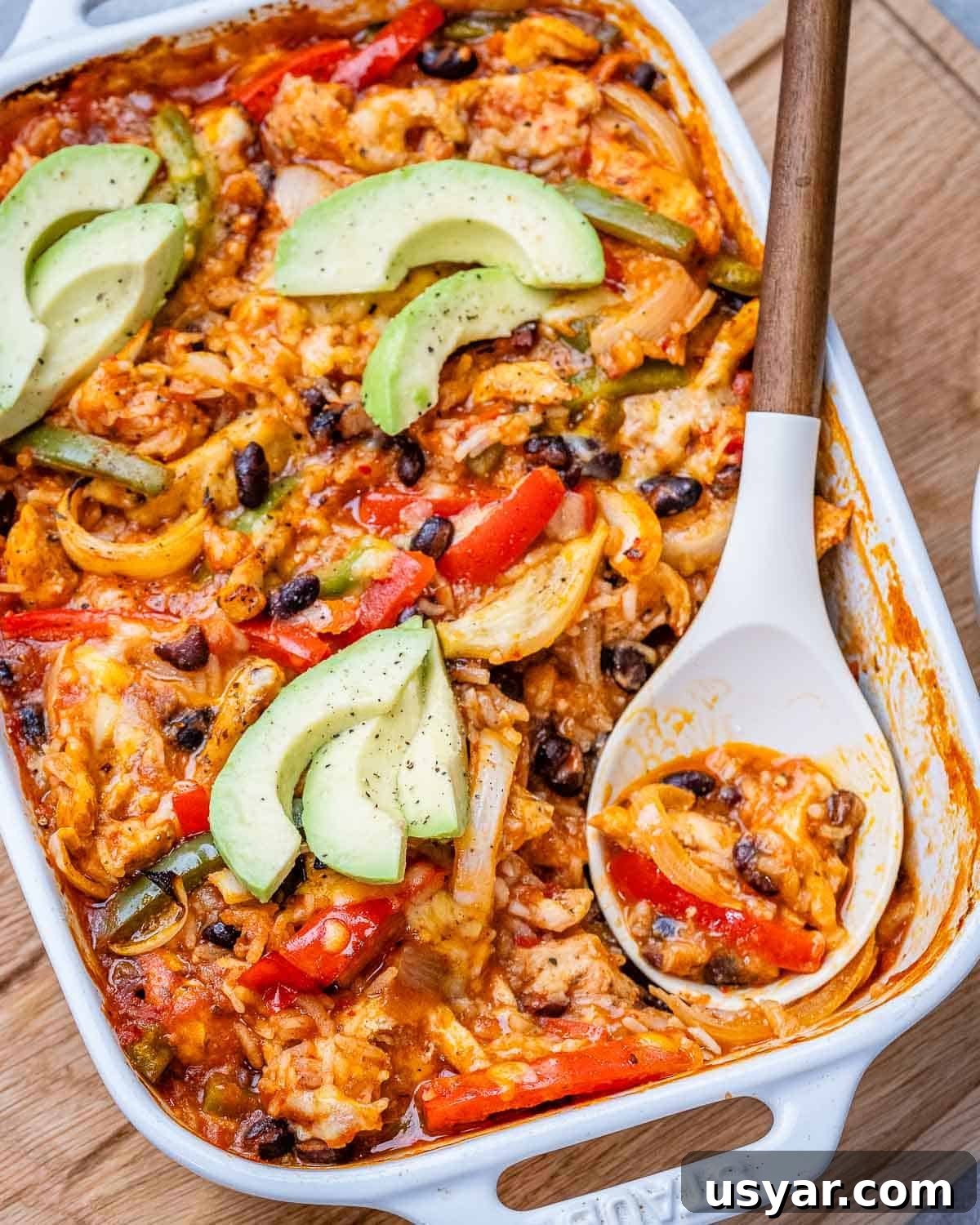 Cheesy Chicken Fajita Casserole Recipe 2 Chicken fajita casserole with rice in a white baking dish with a white serving spoon.