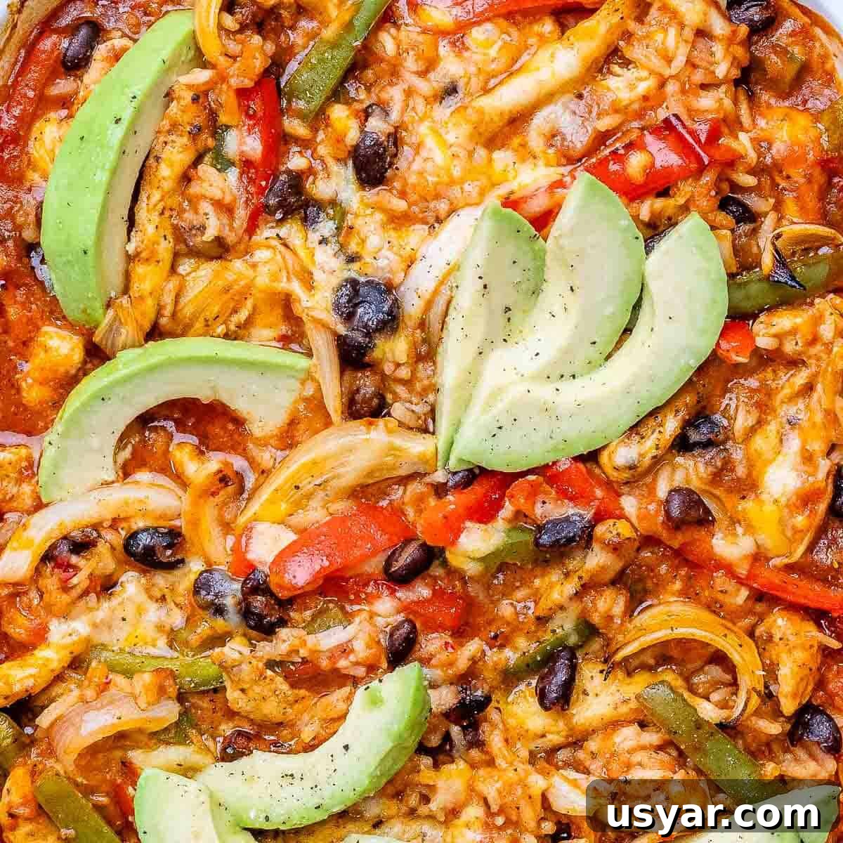 Cheesy Chicken Fajita Casserole Recipe 6 A close up of chicken fajita casserole in a baking dish topped with sliced avocado.