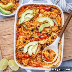 Cheesy Chicken Fajita Casserole Recipe 7 a spoon in a baking dish with chicken fajita, topped with sliced avocado.