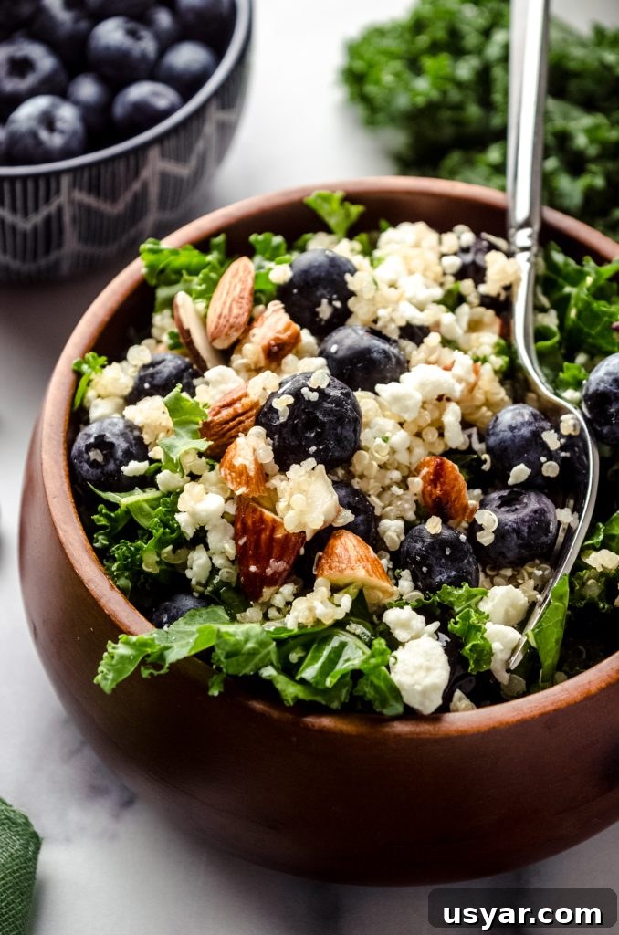 Blueberry quinoa kale salad in a small brown wooden bowl.