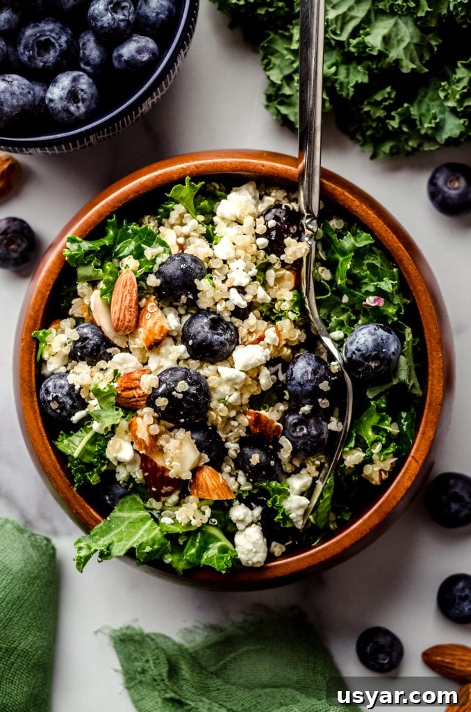 Blueberry quinoa kale salad in a small brown wooden bowl.