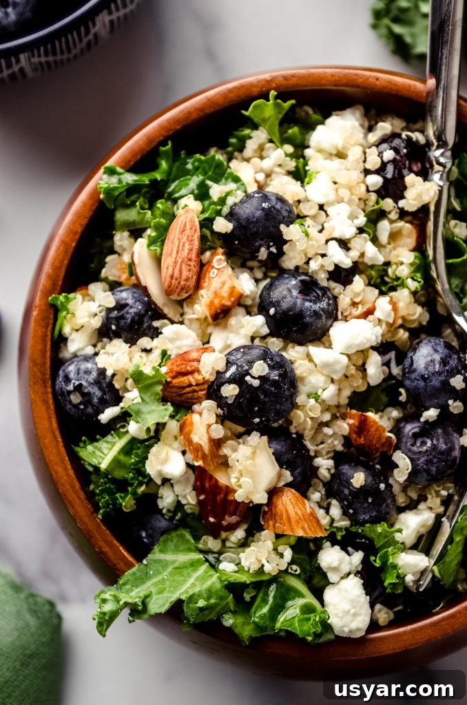 Blueberry quinoa kale salad in a small brown wooden bowl.