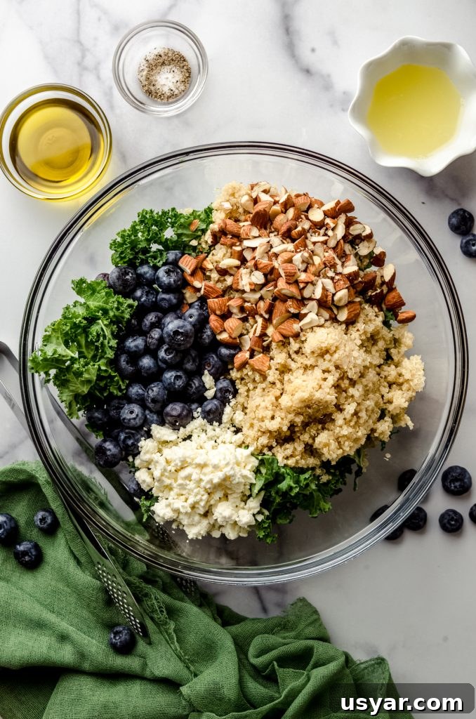 Aerial photo of ingredients for blueberry quinoa kale salad in a large glass bowl.
