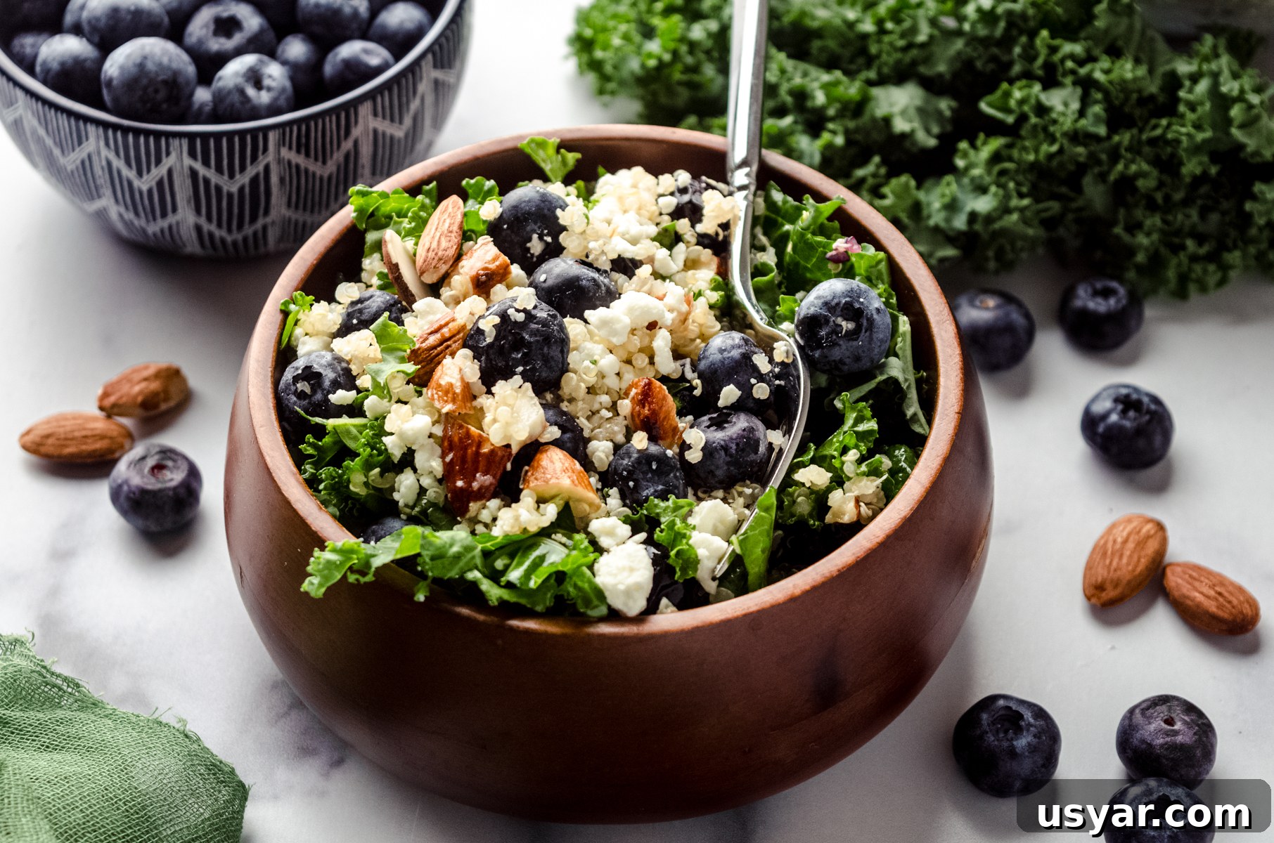 Blueberry quinoa kale salad in a small brown wooden bowl.