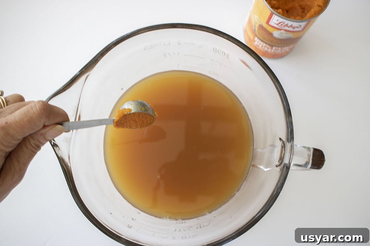 Adding pumpkin to the apple cider caramel mixture.