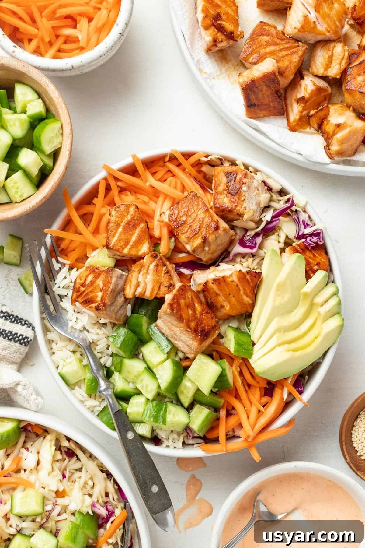 Spicy Mayo Salmon Rice Bowl 9 Seared salmon in a bowl with rice, avocado, carrots, slaw, and a small bowl of spicy mayo on the side.