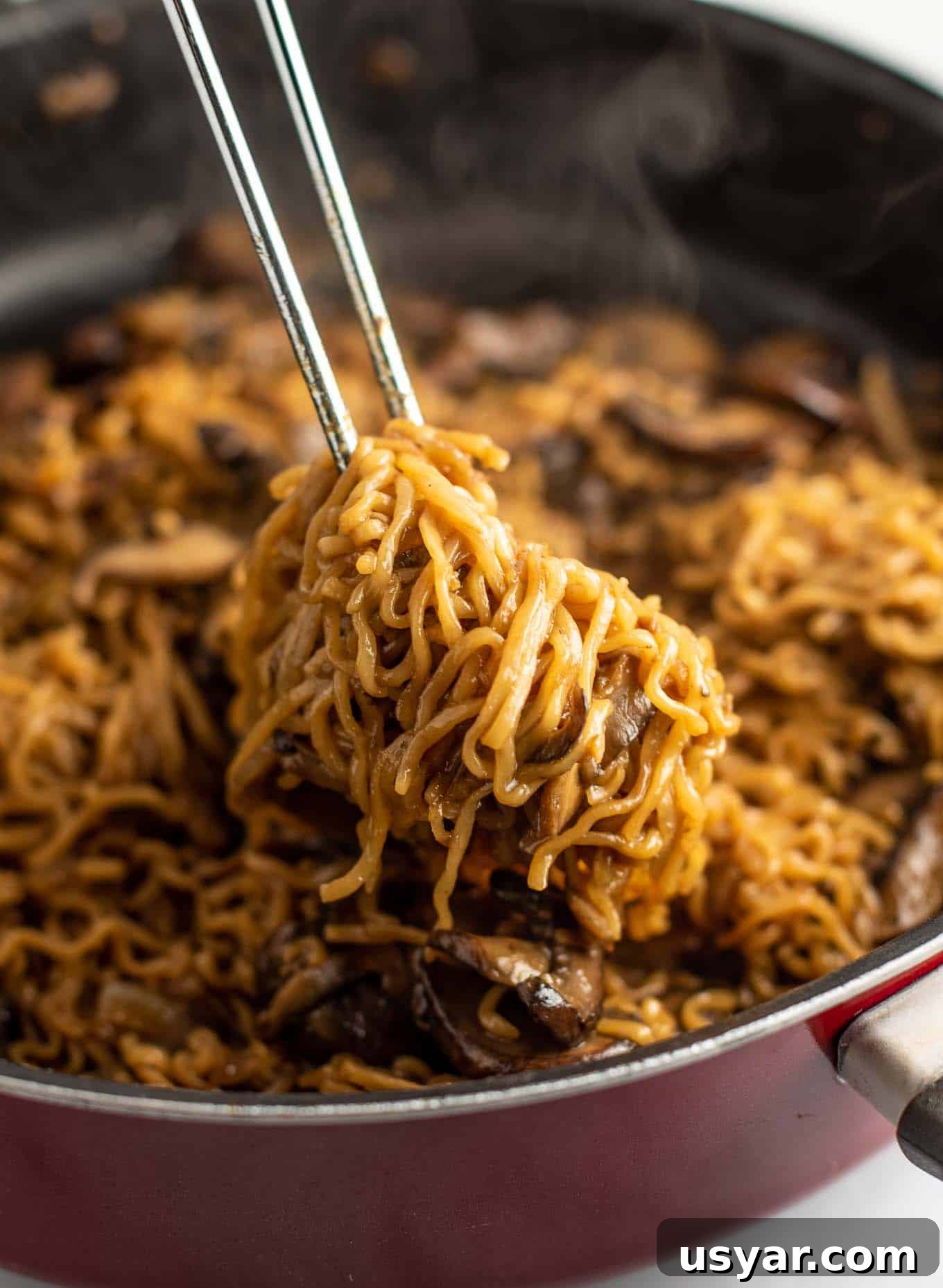 Umami Mushroom Ramen Noodles with Savory Broth 2 tongs pulling ramen noodles from a pan