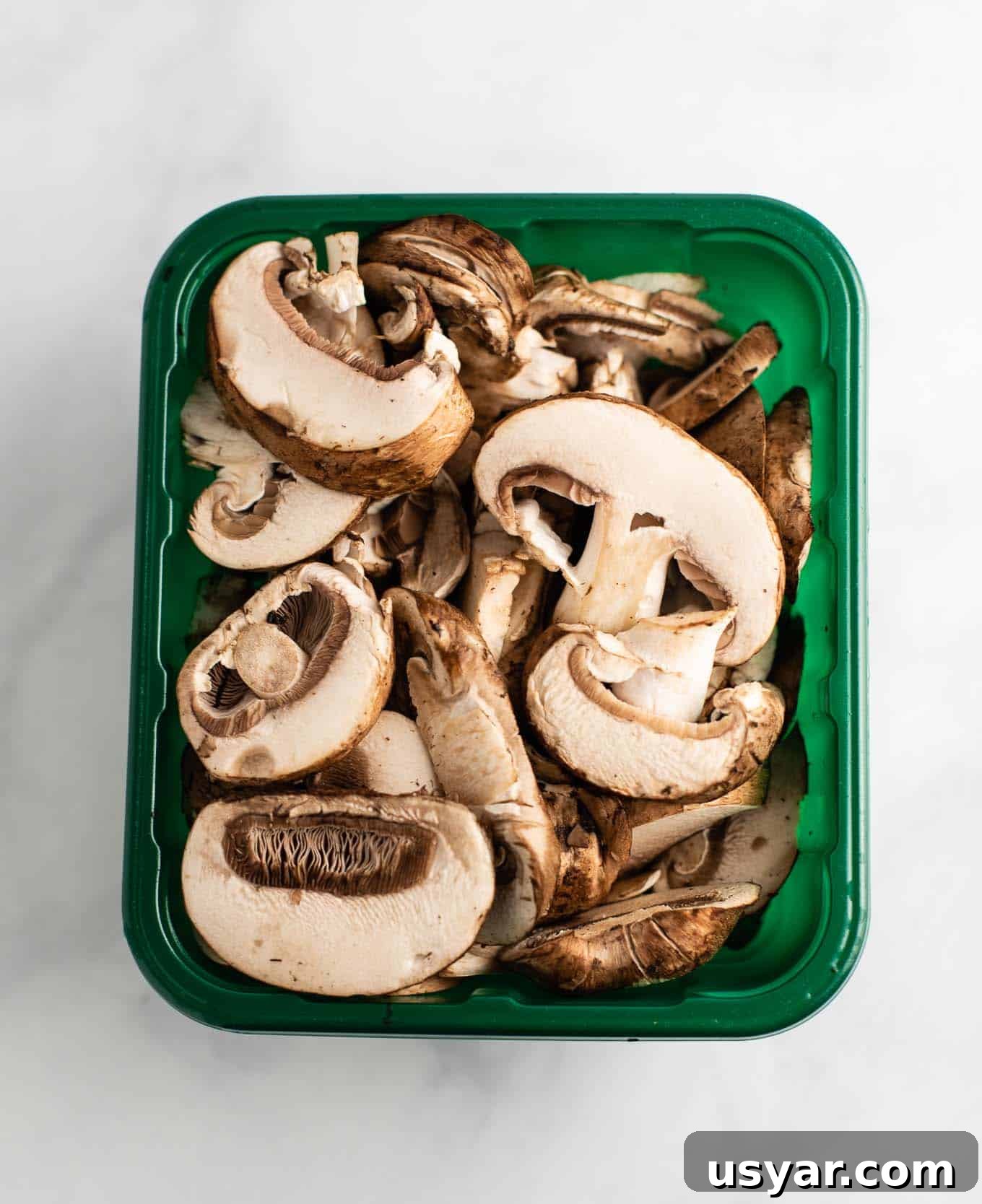 Umami Mushroom Ramen Noodles with Savory Broth 6 sliced portobello mushrooms in a produce container from an overhead view