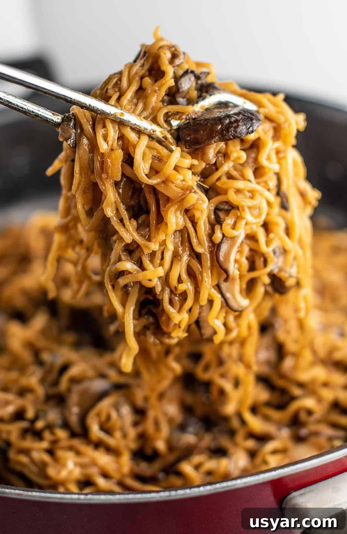 Umami Mushroom Ramen Noodles with Savory Broth 8 ramen noodles with mushrooms being pulled from a pan with tongs