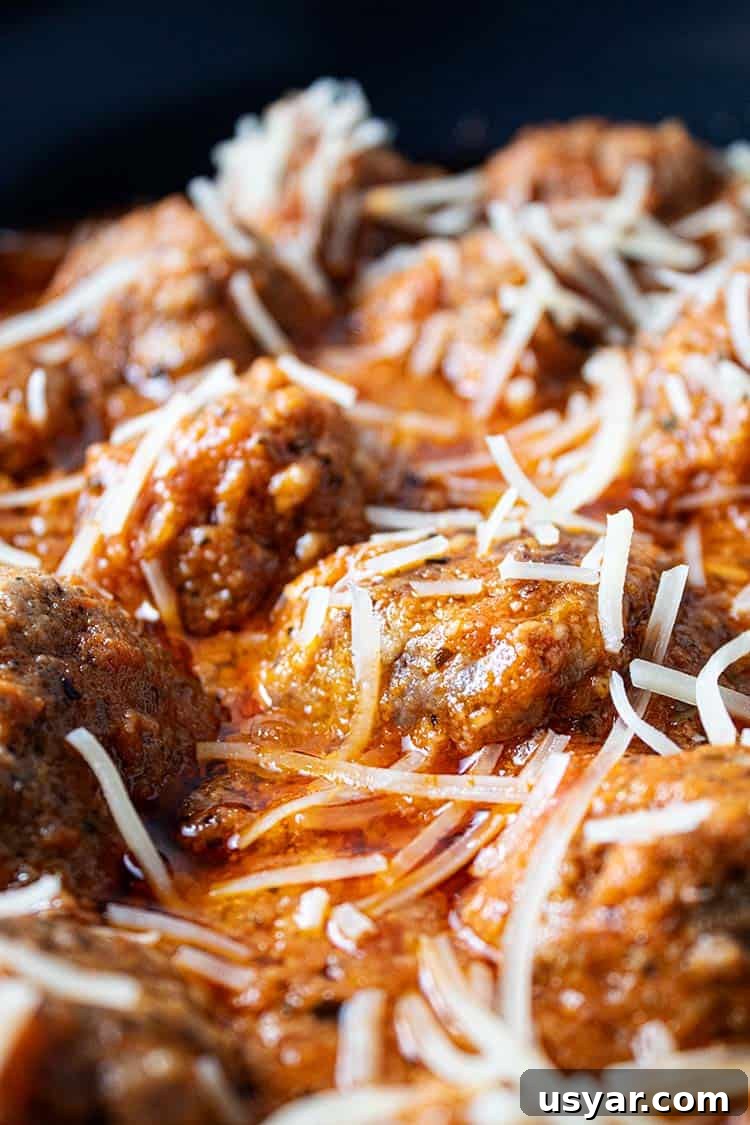 sideview of keto meatballs in marinara sauce topped with shredded parmesan cheese