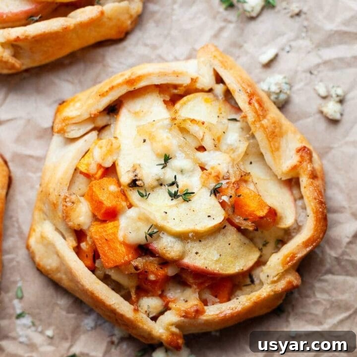 a gluten free savory galette with butternut squash, apples, sweet onions and blue cheese on brown parchment paper