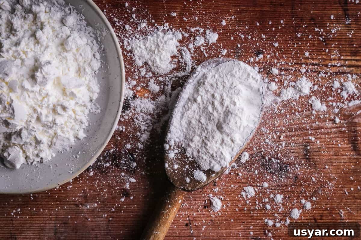 Cornflour vs Cornstarch vs Cornmeal: Key Differences & Uses 4 A spoon of cornflour showing it's white and powdery.