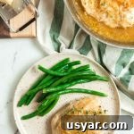 French Onion Skillet Chicken Breasts 8 Overhead view of a plate of skillet French onion chicken breasts smothered with gruyere cheese and served with steamed green beans.