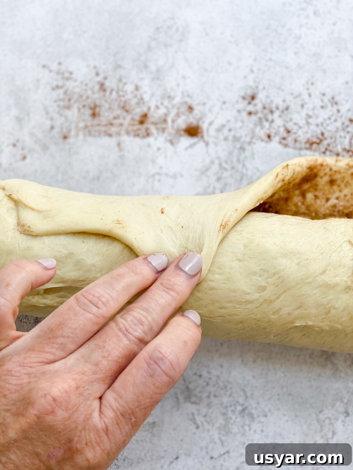 Cinnamon Rolls Stuffed with Apple Pie Filling 11 rolling dough into a log.