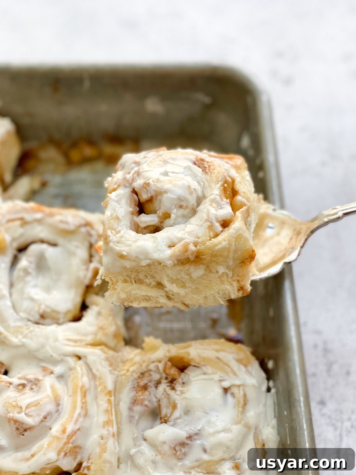 Cinnamon Rolls Stuffed with Apple Pie Filling 15 cinnamon rolls with apple pie filling being taken out of the pan.