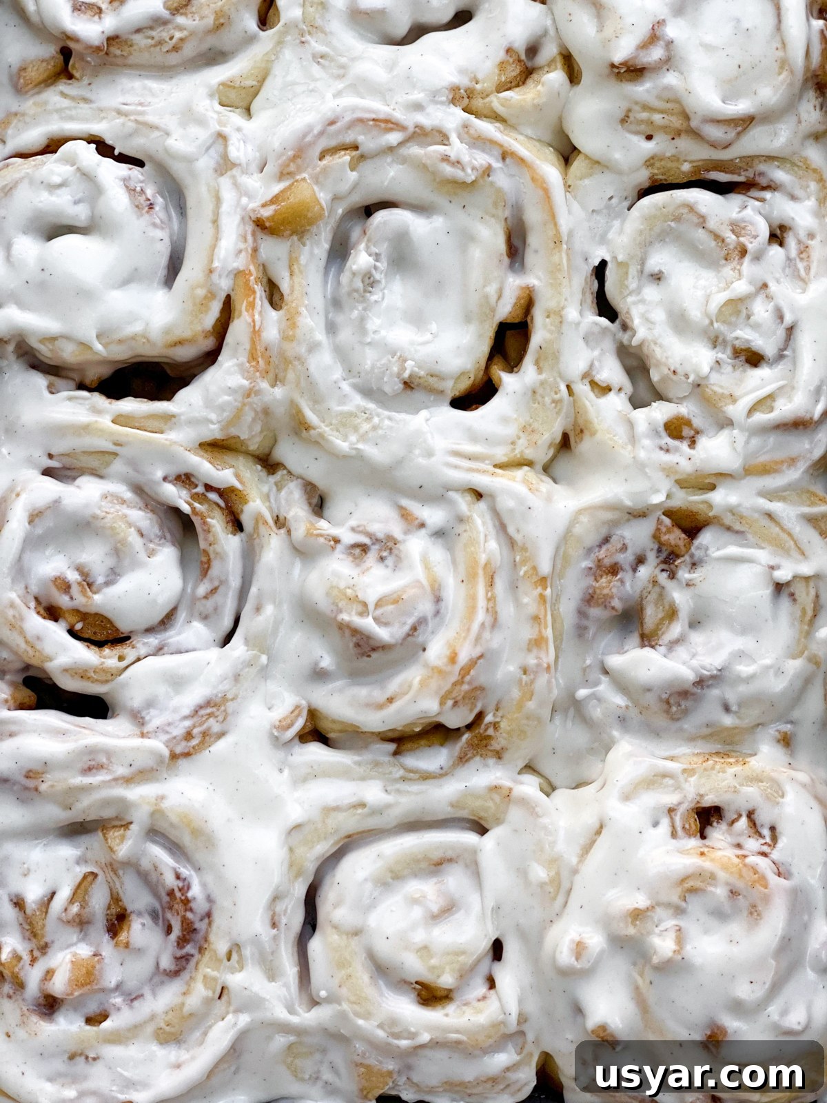 Cinnamon Rolls Stuffed with Apple Pie Filling 16 close up of frosted cinnamon rolls with apple pie filling.