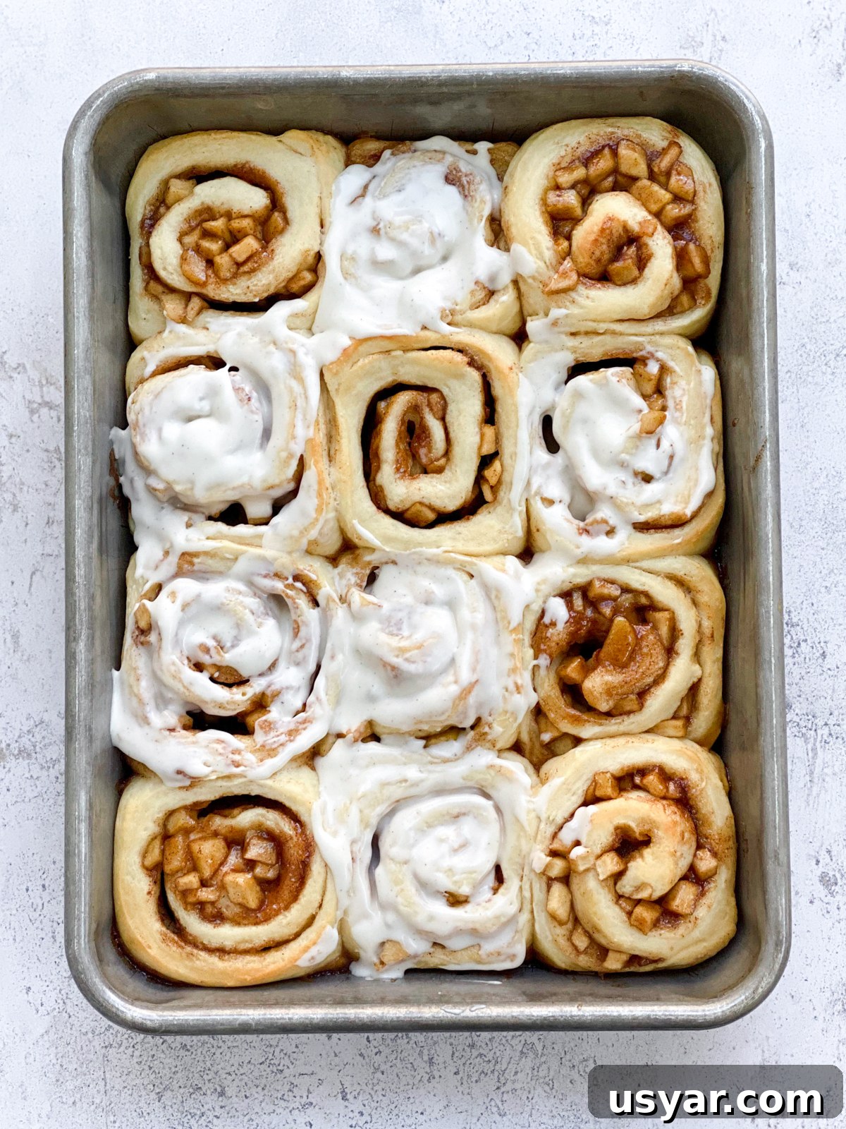 Cinnamon Rolls Stuffed with Apple Pie Filling 3 cinnamon rolls with apple pie filling with some frosted and some not.