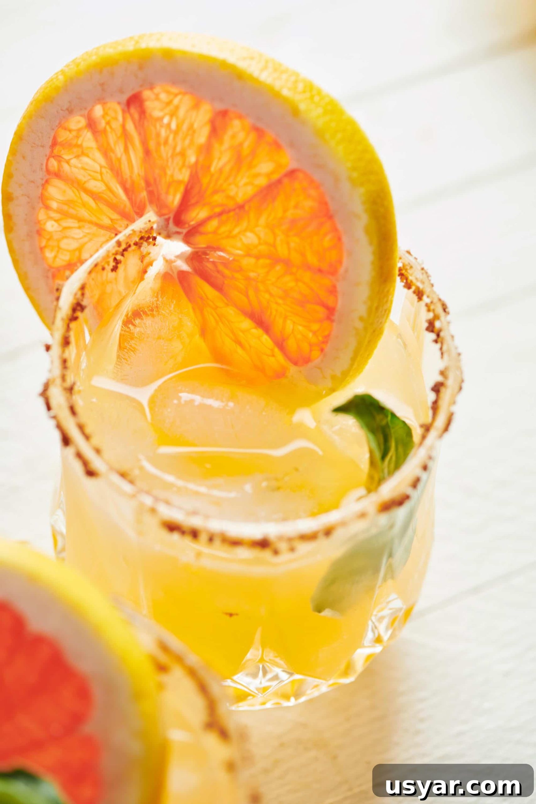 Pomelo and yuzu paloma cocktail in rocks glass with citrus garnish.