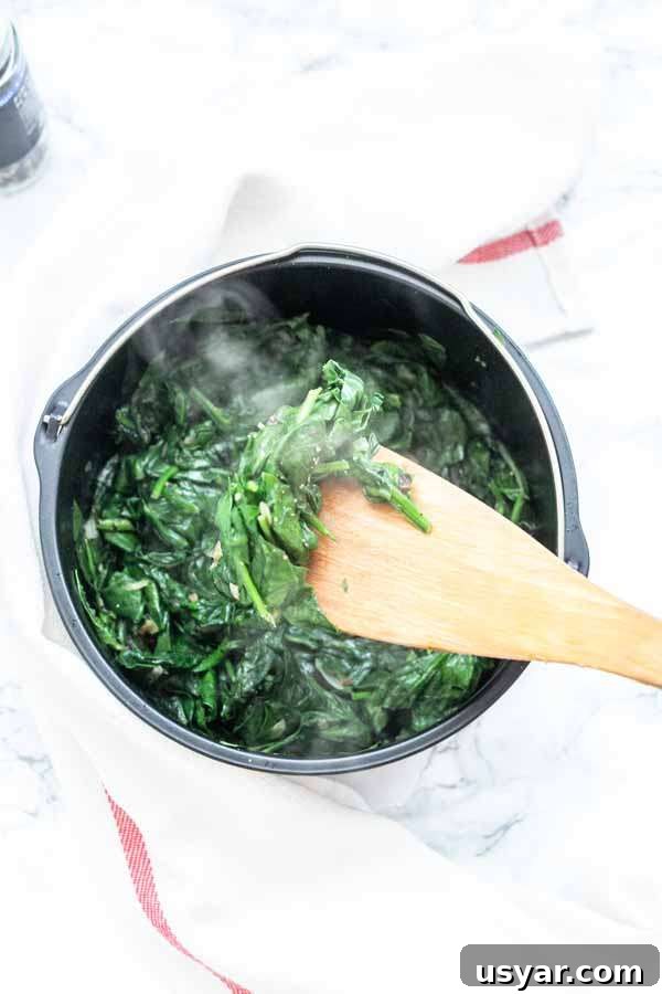Crispy Garlic Air Fryer Spinach 6 Close up of spinach with a wooden spoon for serving the spinach as a side dish.