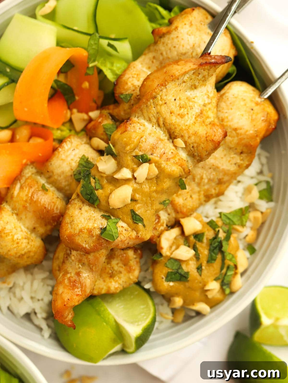 Chicken Satay Skewers topped with peanuts and a side of lime.