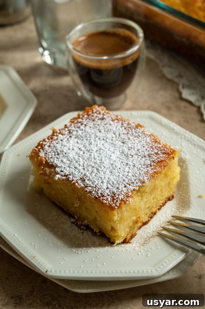 Lemonopita: Greek Lemon Cake with Phyllo 14 A piece of lemonopita cake on a white plate, and topped with a sprinkle of icing sugar, with a Greek coffee next to it.