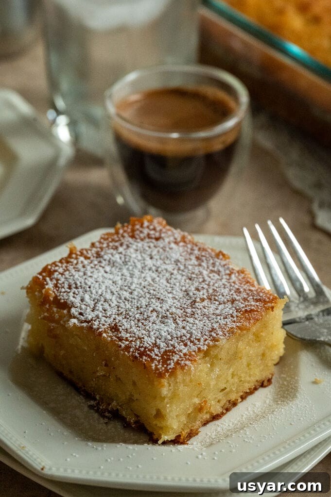 Lemonopita: Greek Lemon Cake with Phyllo 15 A piece of lemonopita cake on a white plate, and topped with a sprinkle of icing sugar, with a Greek coffee next to it.