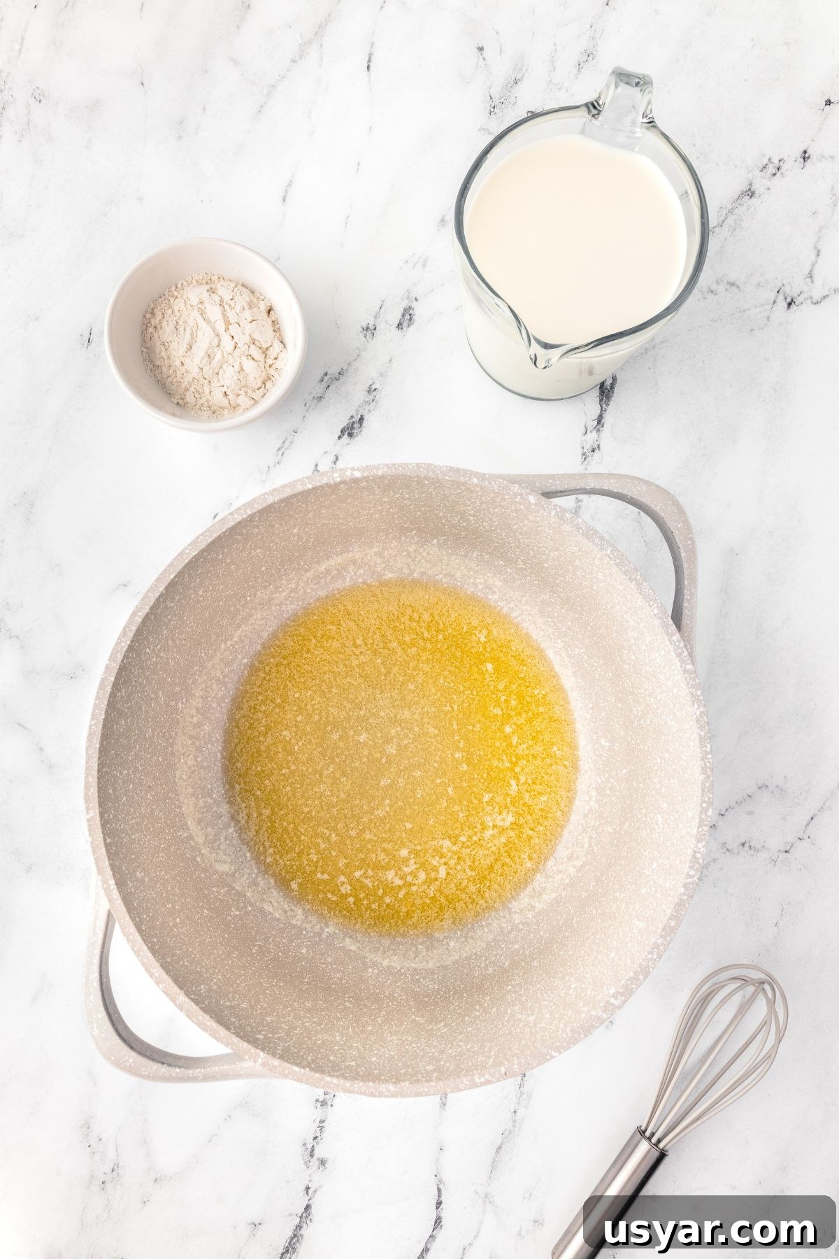 Creamy Stovetop Macaroni and Cheese 5 Butter, flour, milk, and eggs on a white marble surface for baking.